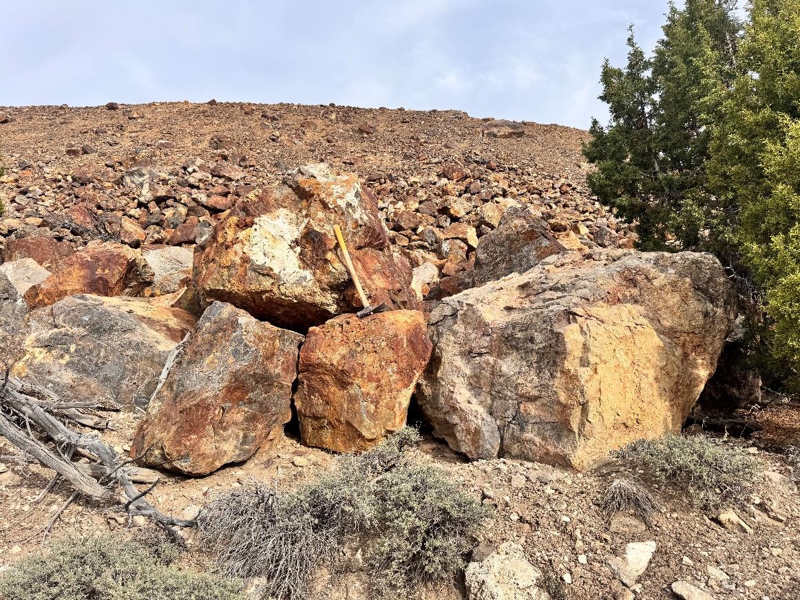 Figure 3 – Picture of the waste dump showing an example of identified antimony mineralization in pre-strip waste dump material. Rock hammer for scale.